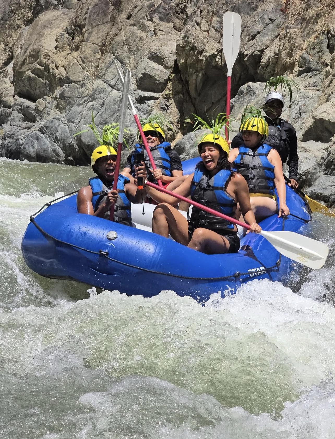 Rafting crew smiling together in a blue raft on the Chili River