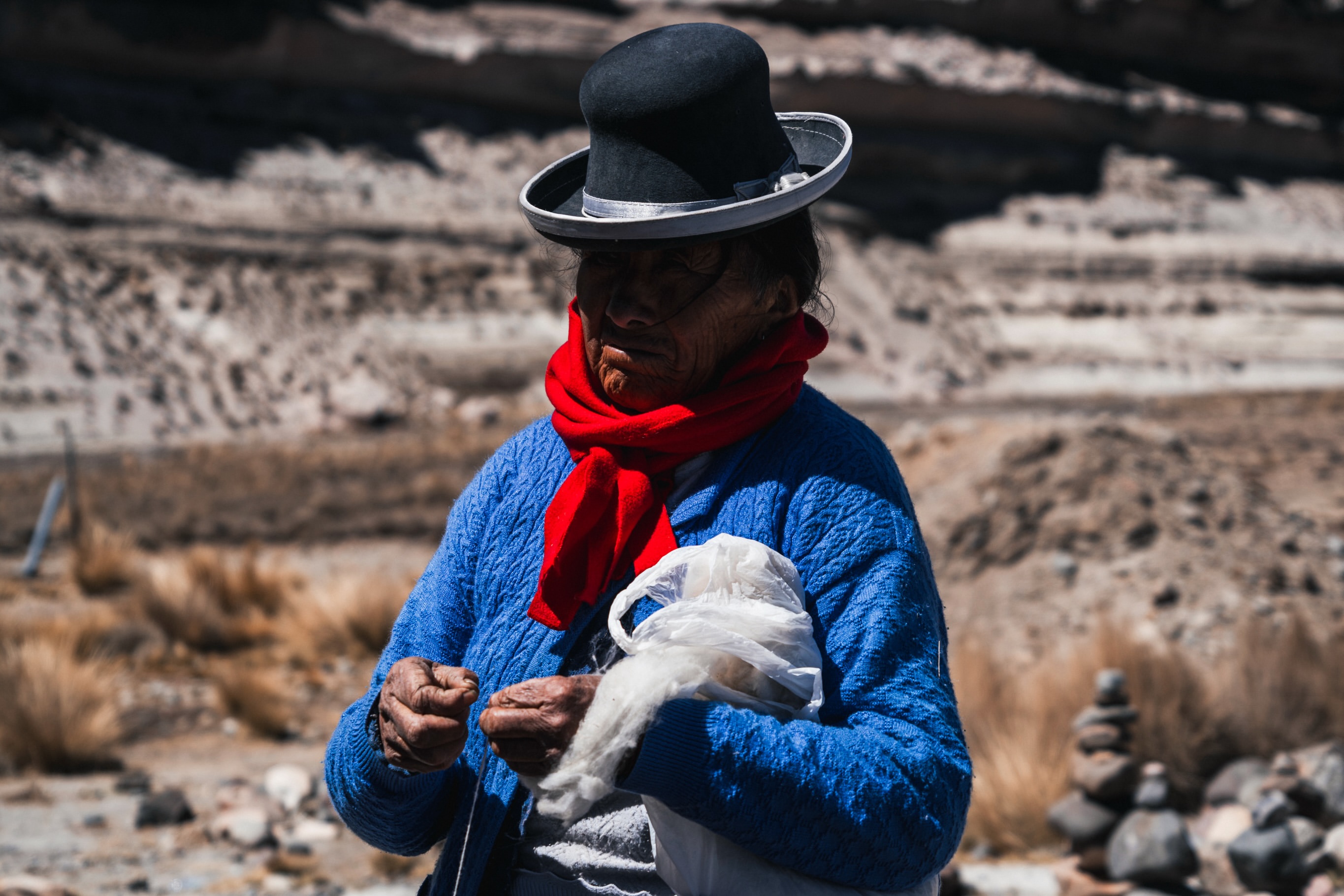Andean artisan in a blue sweater and red scarf