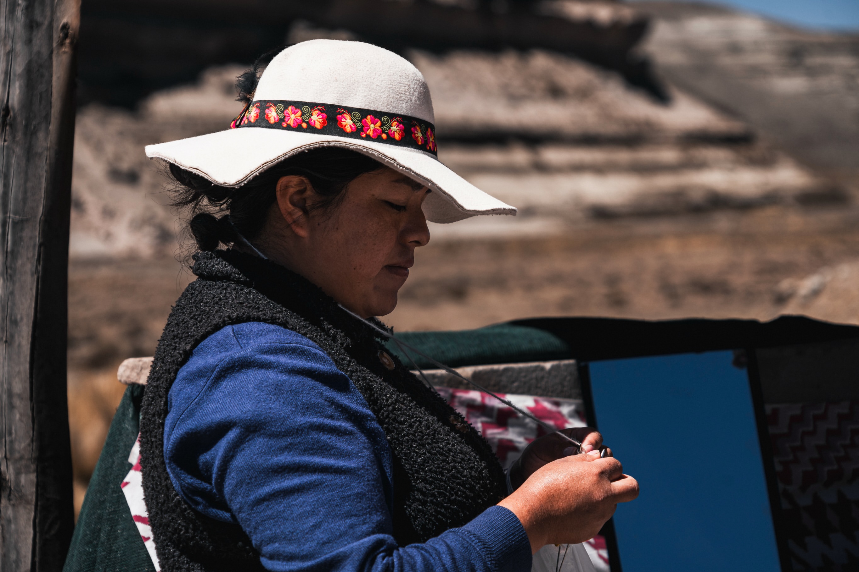 Andean woman wearing a traditional white hat working by hand